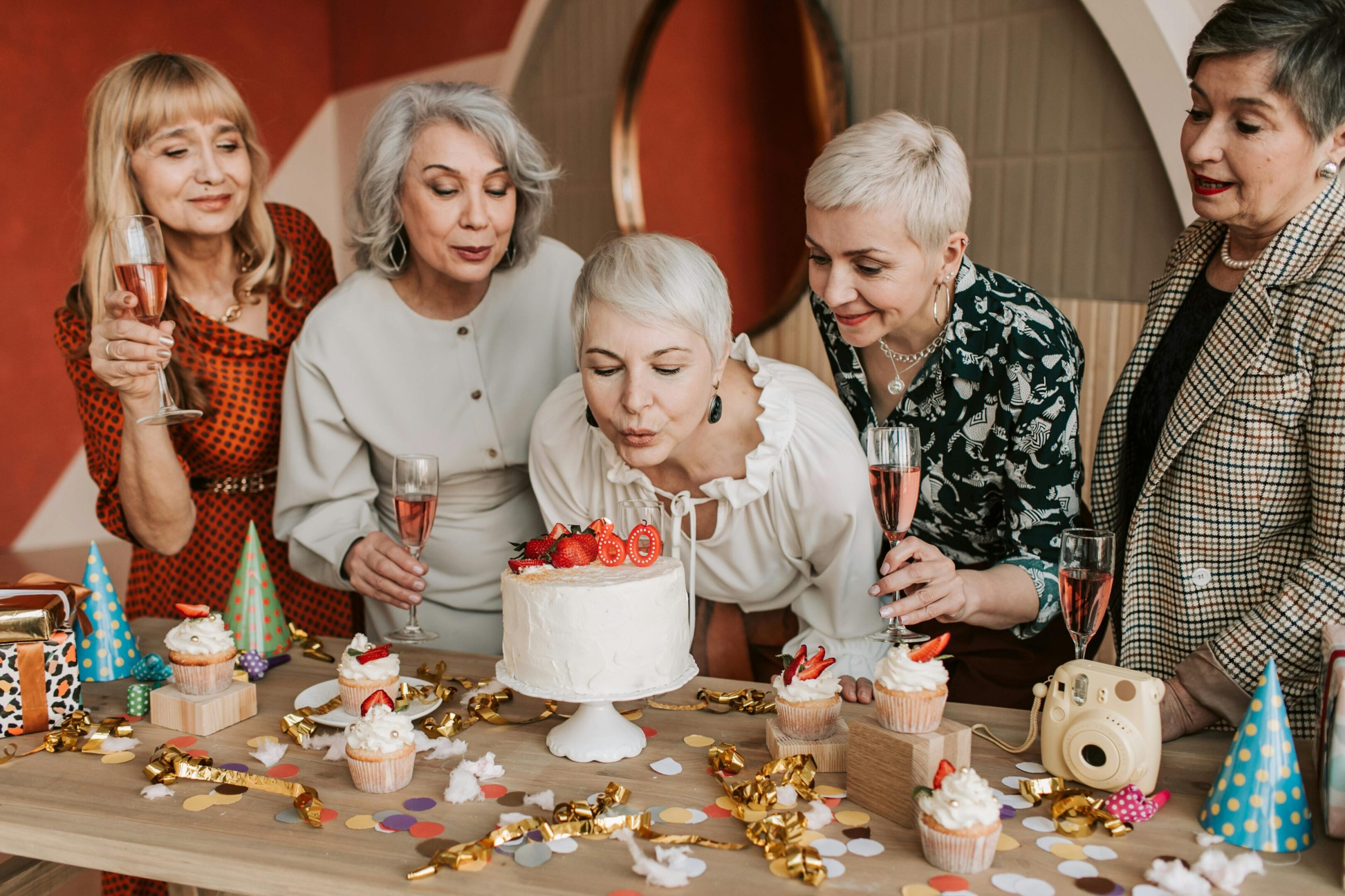 A group of women sitting around a table with cake.